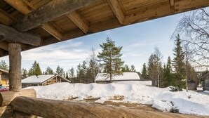 Eine rustikale Holzhütte mit einer Holzterrasse, umgeben von schneebedecktem Boden und Bäumen.