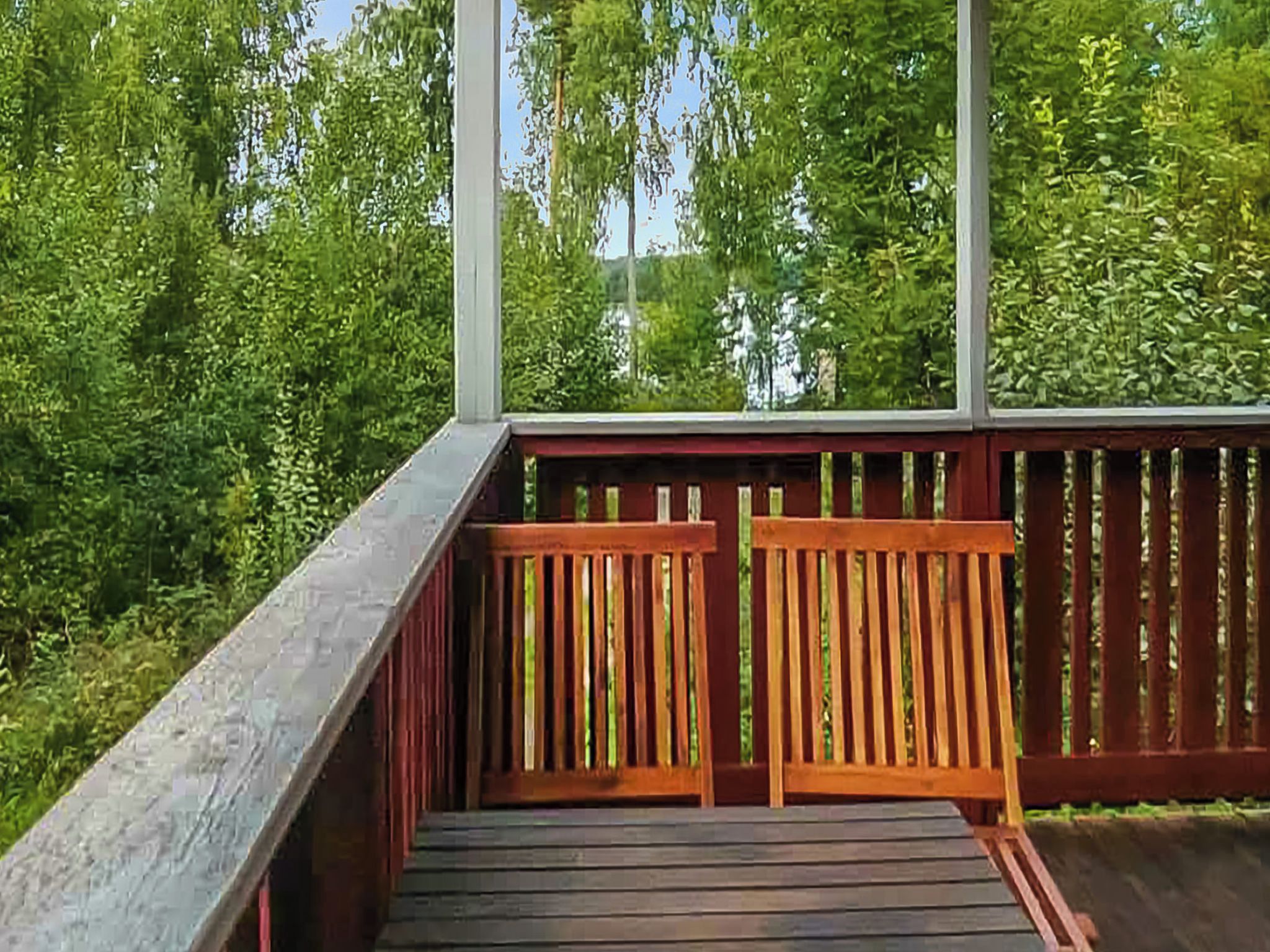 Puinen terassi, jossa on kaide, ja jonka ympärillä on tiheää, vihreää kasvillisuutta.