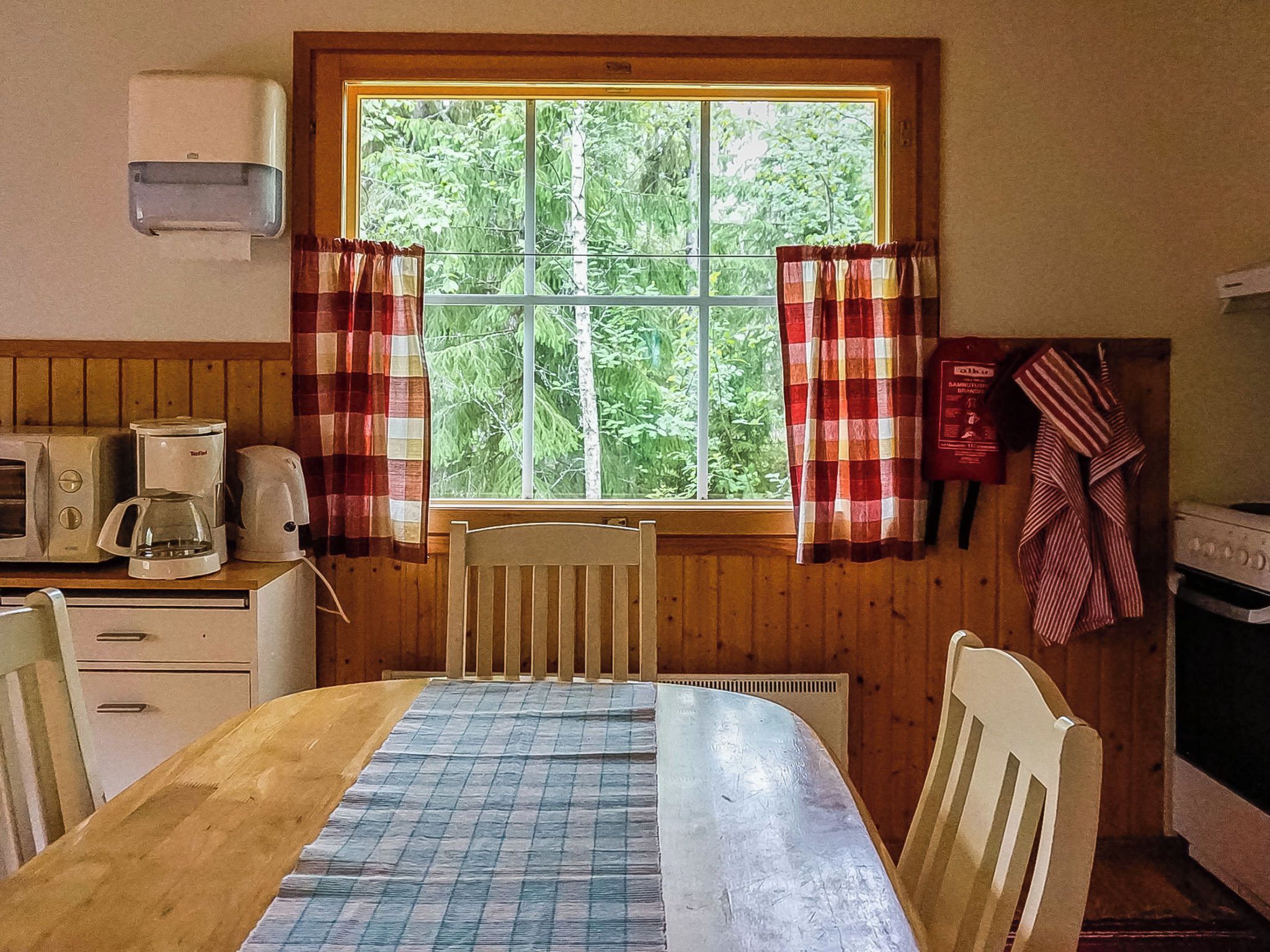 Pieni keittiö, jossa on ikkuna, mikroaaltouuni, vedenkeitin ja liesi.