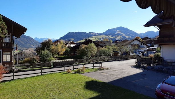 A residential area with houses, a wooden fence, and a car parked on the street. - Mösli (Zimmerli) by Interhome (Zweisimmen)