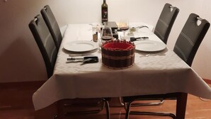A dining table set with plates, cutlery, a wine bottle, and a candle. - Mösli (Zimmerli) by Interhome (Zweisimmen)
