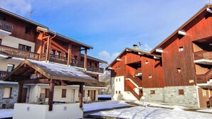 Un edificio de estilo chalet de madera con balcones y una zona de estar al aire libre cubierta.