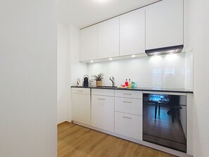 A modern kitchen with white cabinets, a black countertop, and a built-in dishwasher.