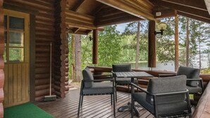 A wooden deck with a table and chairs, overlooking a lake. - Salmela by Interhome (Puumala)