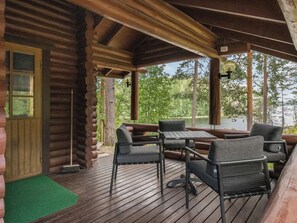 A log cabin with a wooden deck, outdoor seating, and a view of a lake.