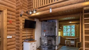 A log cabin interior with a stone fireplace, wooden walls, a television, and a dining area. - Salmela by Interhome (Puumala)