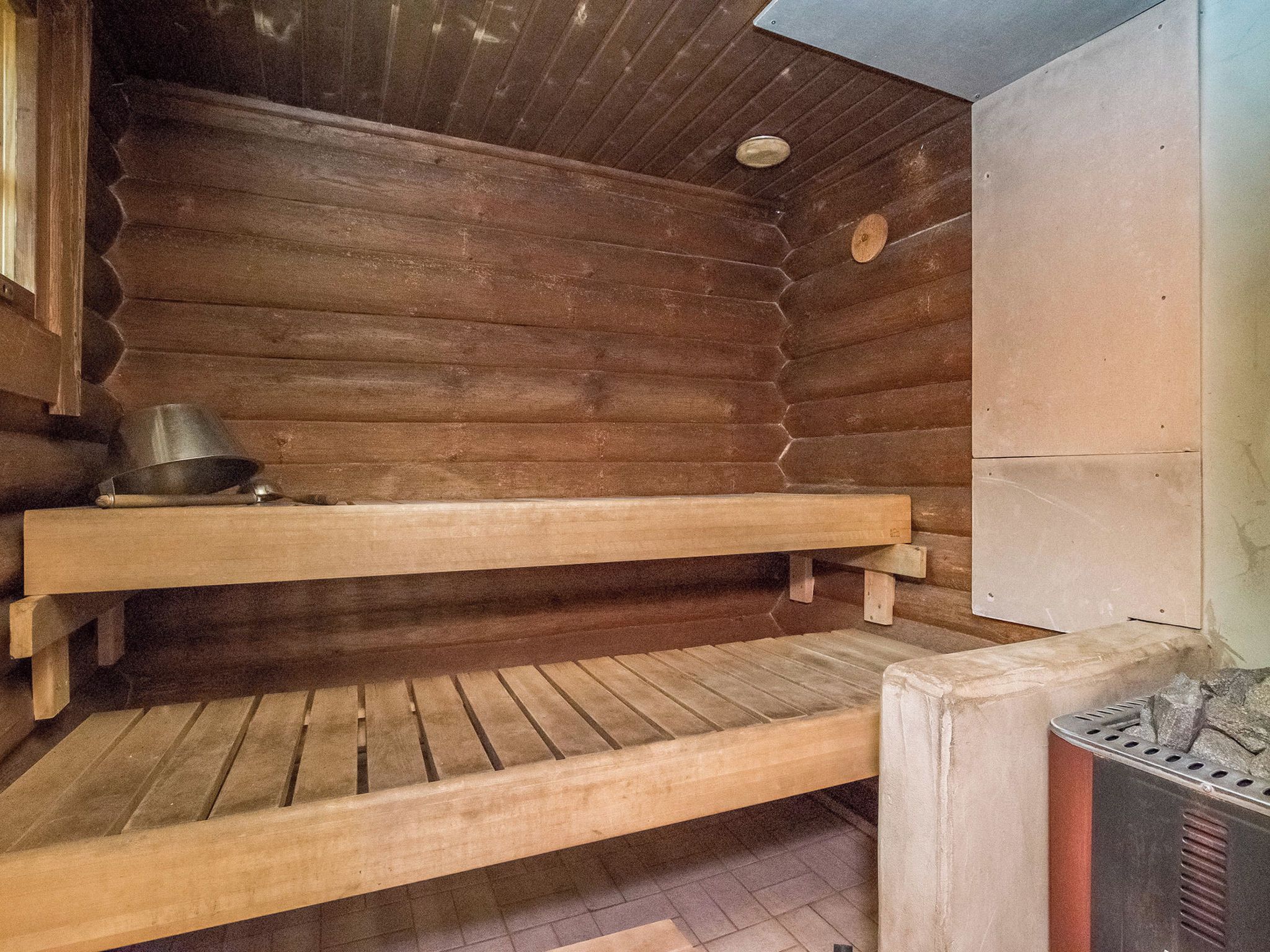 Una sauna amb seients de fusta i un escalfador metàl·lic.