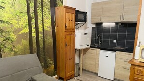 A compact kitchen with a microwave, a small refrigerator, and wooden cabinets. - Le Savoisien by Interhome (Chamonix)