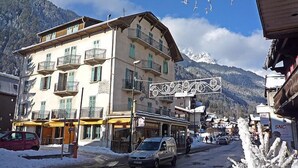 A multi-story building with balconies, a restaurant sign, and a mountain backdrop. - Le Savoisien by Interhome (Chamonix)