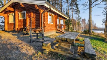 A log cabin with a picnic table and a bicycle parked outside.