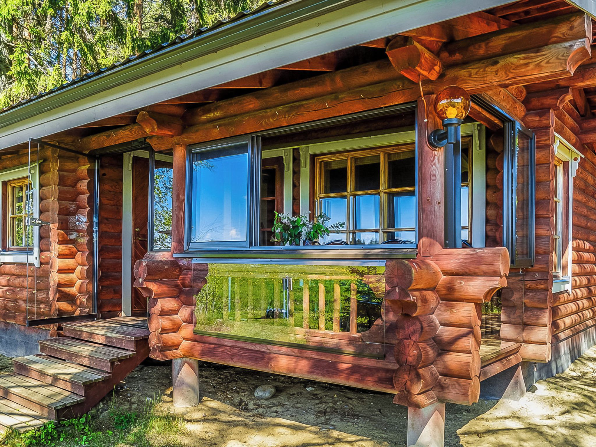 A log cabin with a porch, large windows, and a wooden railing.