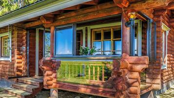 A log cabin with a porch, large windows, and a wooden railing.