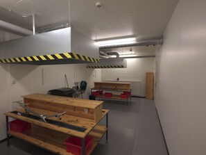 Et værksted med arbejdsbænke, værktøj og opbevaringskasser.