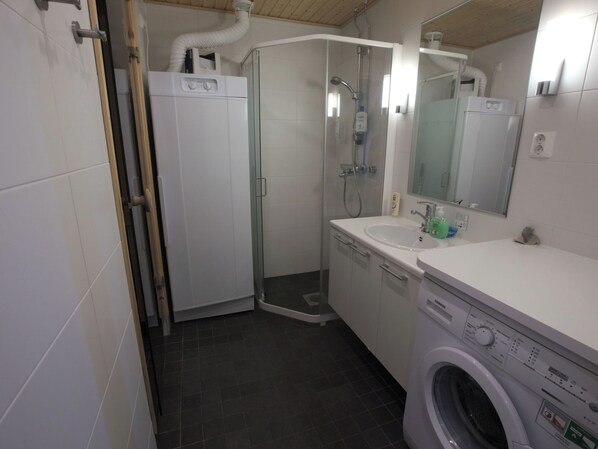 Ein modernes Badezimmer mit einer Duschkabine, einem Waschbecken und einer Waschmaschine.