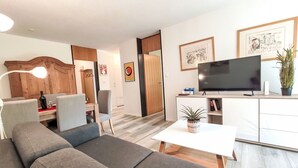 Ein modernes Wohnzimmer mit einer Couch, einem Couchtisch, einem Fernseher und einem Schreibtisch mit Stuhl.