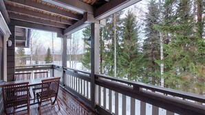 Une terrasse en bois avec une table et des chaises, donnant sur une zone boisée.