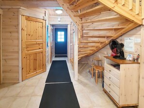 A wooden interior with a black mat leading to a door, wooden furniture, and a fan on a shelf. - Kultakoto a by Interhome (Nilsiä)