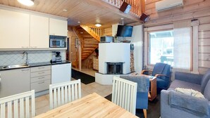 Une cuisine compacte dotée d’appareils électroménagers modernes, un coin repas avec une table en bois et un espace de vie chaleureux avec un canapé et un téléviseur.