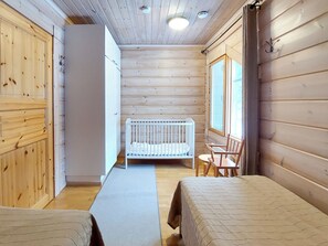 Ein Ferienhausinnenraum mit einem Reisebett, einem Tisch und einem Stuhl.