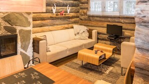 A log cabin interior with a sofa, coffee table, TV, and fireplace.