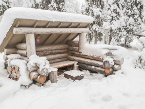 A snow-covered wooden cabin with a bench and a lantern. - Ykkösruka 3, 3a by Interhome (Kuusamo)