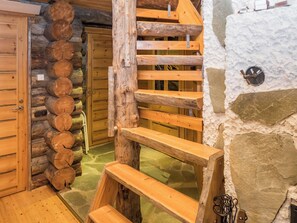 A log cabin interior with a wooden staircase, a stone wall, and a door leading to another room. - Ykkösruka 3, 3a by Interhome (Kuusamo)
