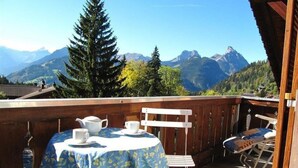 Eine Holzterrasse mit Tisch für zwei Personen, mit Blick auf eine Berglandschaft.