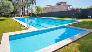A rectangular swimming pool with a clear blue water surface, surrounded by a well-maintained grassy area and a low stone wall. - Edificio Blanqueries by Interhome (Calella)