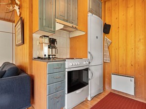 Una cocina compacta con cafetera, horno y refrigerador pequeño.