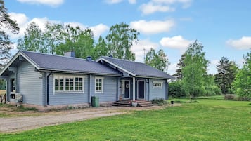 A single-story house with a front porch, a chimney, and a grassy yard.
