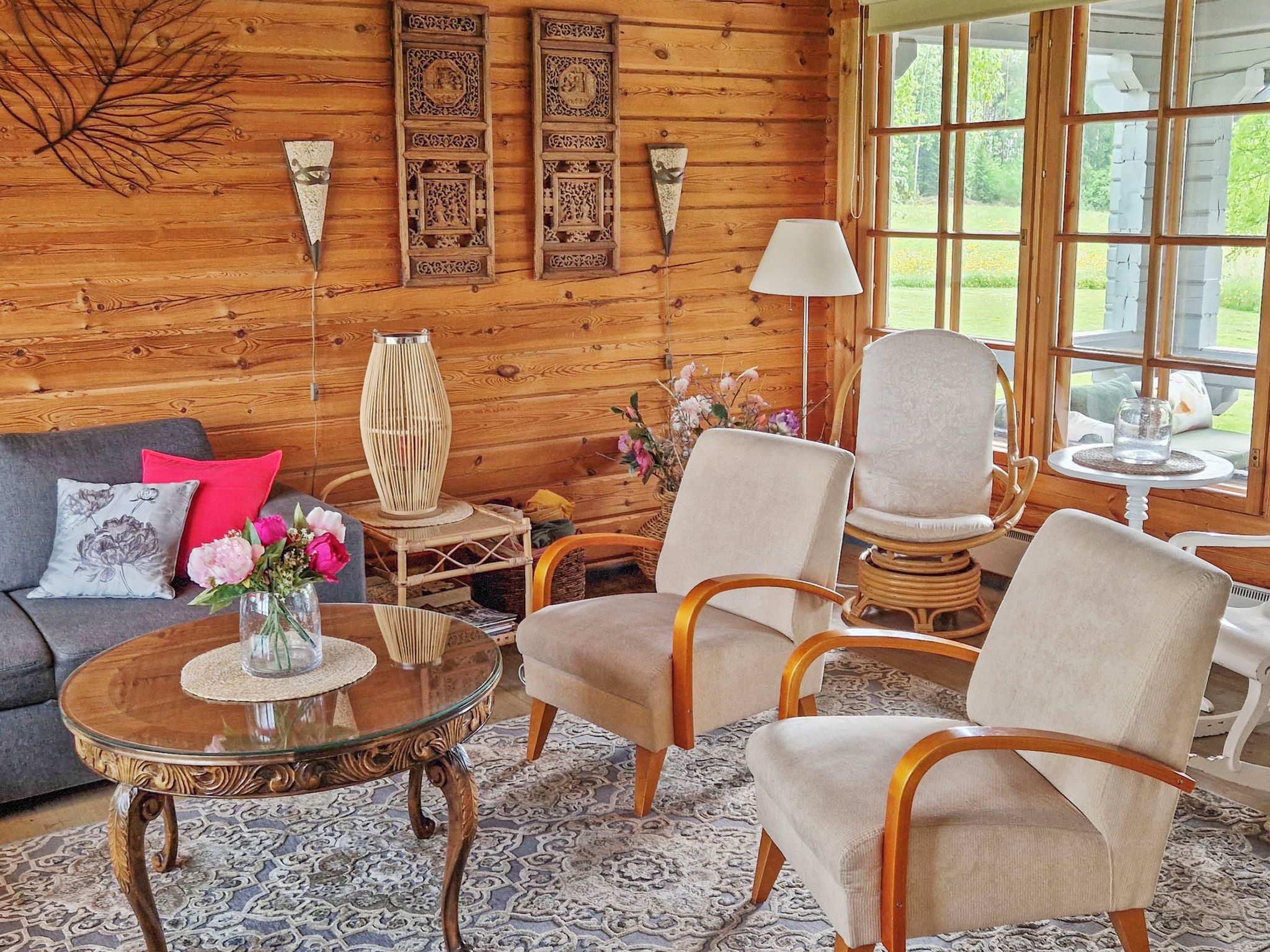 A cozy room with a wooden wall, a sofa, two armchairs, a coffee table, and a lamp.