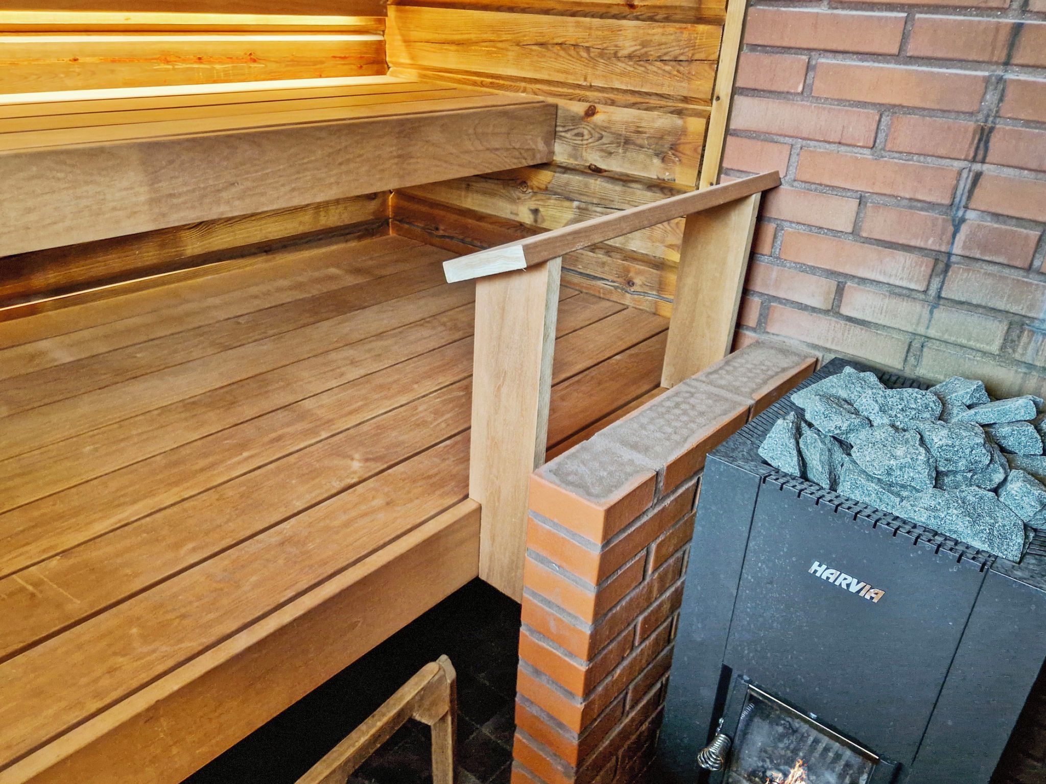 En sauna med træbænke og en murstensvæg.