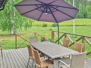 Eine Holzterrasse mit Tisch und Stühlen, umgeben von einem Geländer.