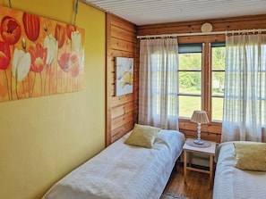 Ein Zimmer mit zwei Einzelbetten, einem kleinen Tisch mit einer Lampe und einem Bild an der Wand.
