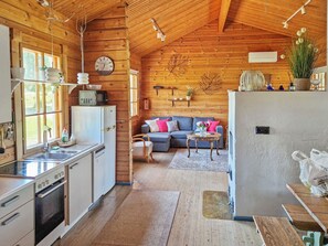 L’intérieur d’une cabane comprenant une cuisine, un coin repas et un salon.