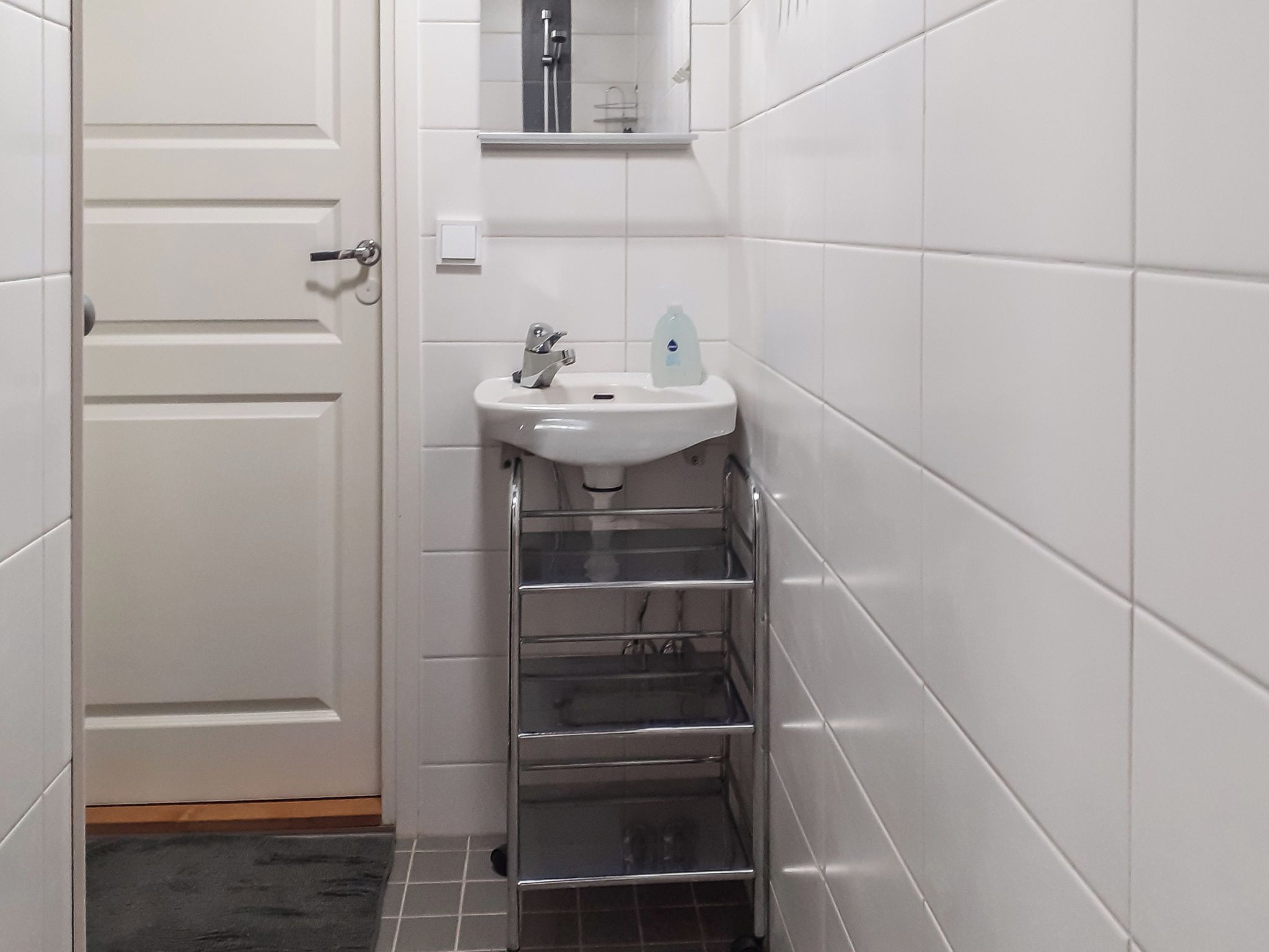 A bathroom with a white sink, a mirror, and a towel rack.