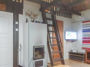 A room with a white wall, a wooden ladder, a television mounted on the wall, and a small table with a radio. - Kaukosaaren ahonlaita by Interhome (Kuusamo)