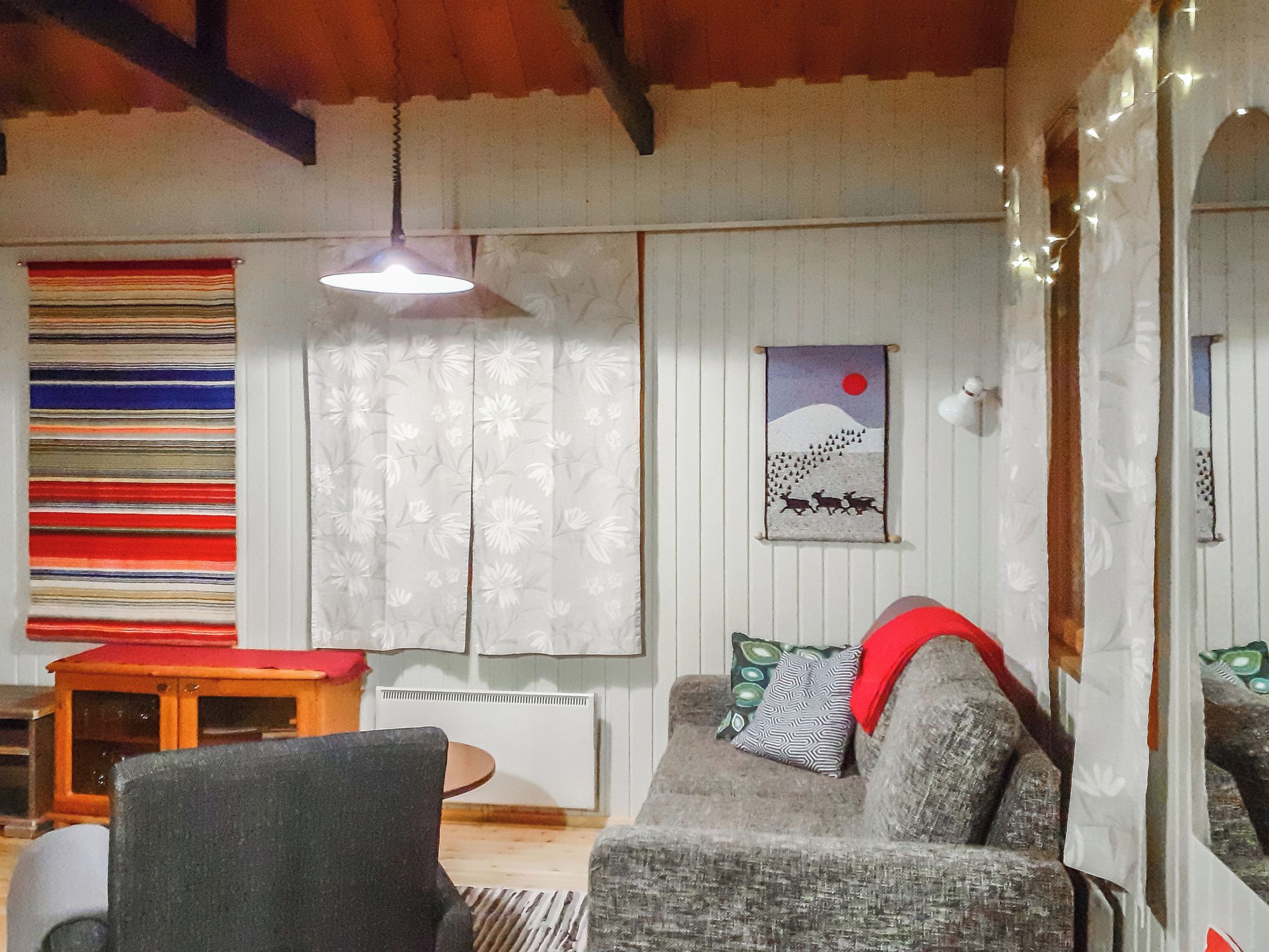 Een gezellige woonkamer met een bank, een kleine tafel en een hanglamp.