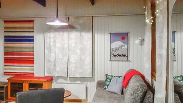 Een gezellige woonkamer met een bank, een kleine tafel en een hanglamp.