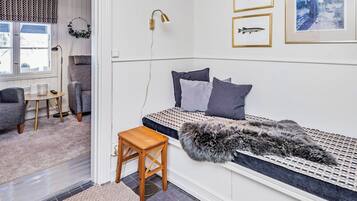 Een gezellige slaapkamer met een bed, een klein houten krukje, een bont plaid en kunst aan de muur.