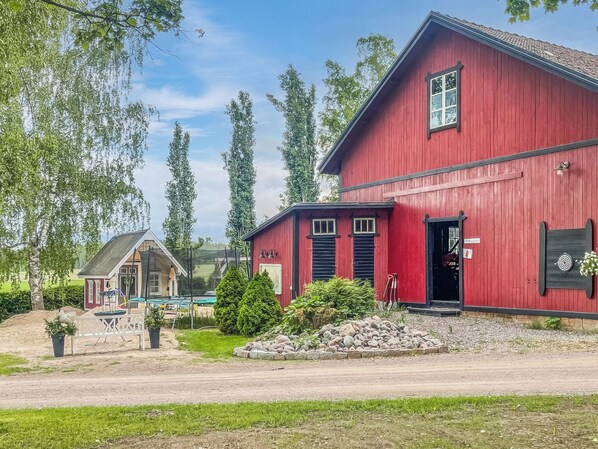 A red building with a two-story structure, a small adjacent building, and a gravel driveway. - Punatulkku by Interhome (Somero)