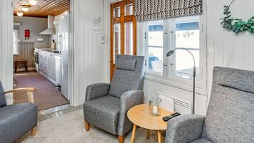 A cozy room with two grey armchairs, a small wooden table, and a window with a view.