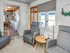 Una habitación acogedora con dos sillones grises, una pequeña mesa de madera y un ventanal.