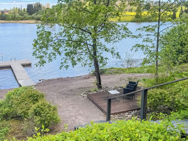 Terraza junto al lago con mobiliario exterior y un muelle que se adentra en el agua.
