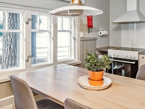 Una cocina moderna con una mesa de madera, estufa a gas y ventana con vistas a un paisaje nevado.
