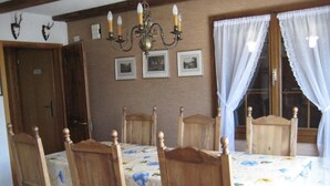 Un comedor con una mesa y sillas de madera, una araña y cuadros enmarcados en la pared.