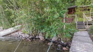 Une jetée en bois s’avance dans un ruisseau aux eaux claires, et une petite construction en bois se trouve sur la droite.