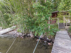 Un muelle de madera se adentra en un arroyo cristalino, con una pequeña construcción de madera a la derecha.
