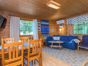 A wooden cabin interior with a dining table, chairs, a sofa, and a small round table. - Illanvirkku by Interhome (Punkaharju)