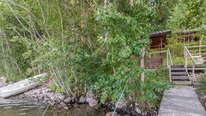 Een houten steiger die zich uitstrekt over een rustige rivier, omringd door weelderige begroeiing en een klein houten gebouw.